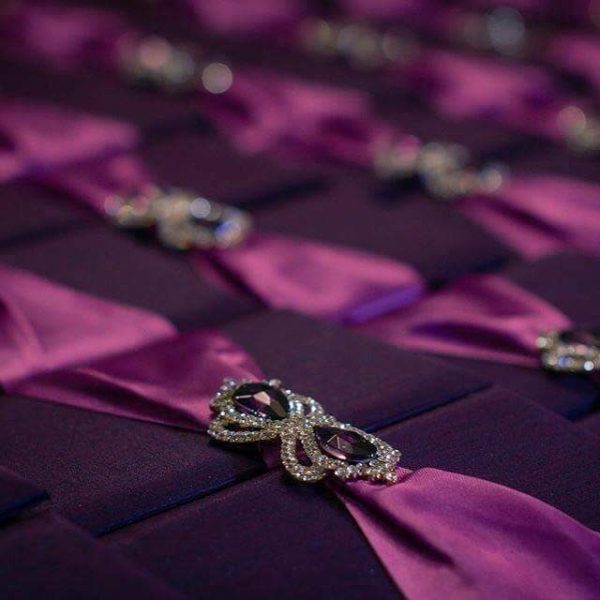 Purple silk boxed wedding invitation design featuring crown brooch embellishment