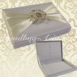 white boxed wedding invitation with large brooch embellishment