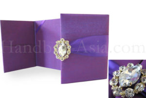 Purple wedding invitation folder with brooch