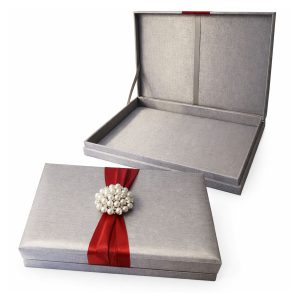 silver silk invitation box with red ribbon and large pearl brooch embellishment