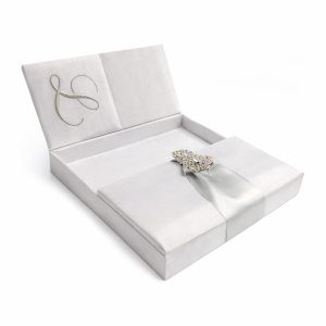 White gatefold silk invitation box with rhinestone clasp and monogram embroidery