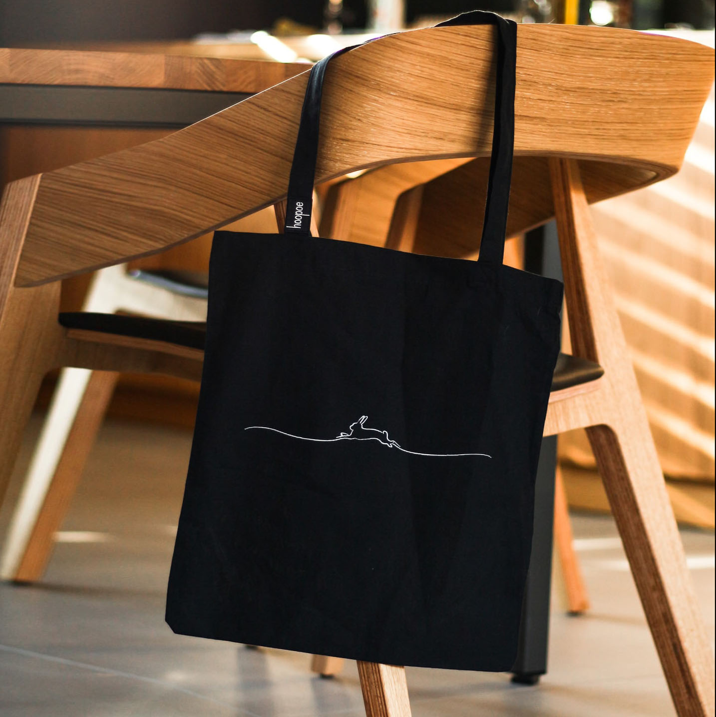 Pictured is an example of our cotton shopping bag in black with white custom printed graphic